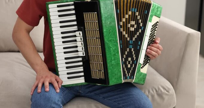 Man playing piano accordion at home, closeup