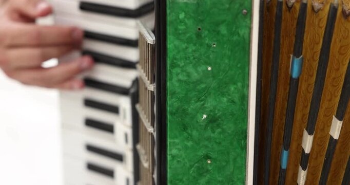 Man playing piano accordion at home, closeup. Camera moving right