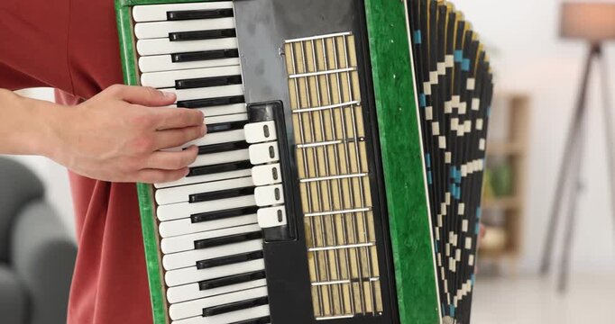 Man playing piano accordion at home, closeup