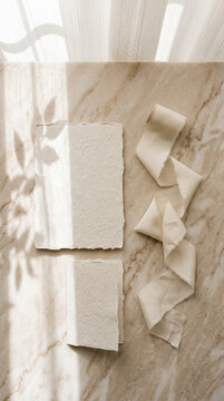 Flat lay wedding stationery card mockup on beige marble counter &mdash; Deckled edge handmade paper with elegant silk ribbon