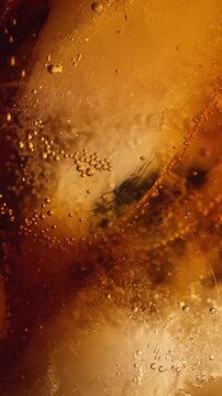 Cola soda being poured extreme closeup vertical video footage showing carbonation bubbles golden amber liquid and ice refreshing drink.