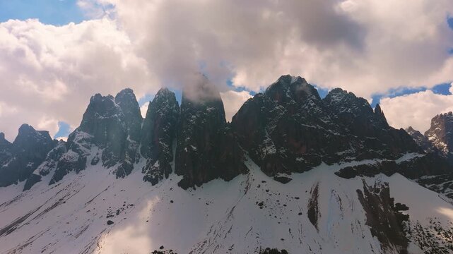 Odle mountain peaks within Puez-Geisler Nature Park. Clouds moving quickly, Dolomites aerial drone
