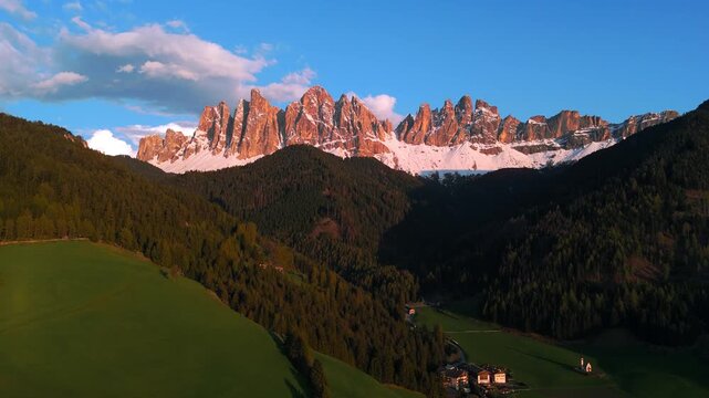 Epic sunset over Odle peaks in Puez-Geisler. Glowing red mountain towers in Val di Funes, Dolomites