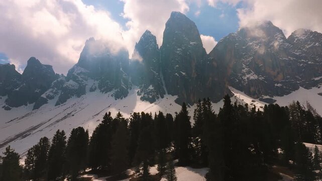 Snow capped Odle peaks in the Puez-Geisler region with dense pine tree forest. Italian Dolomites in spring