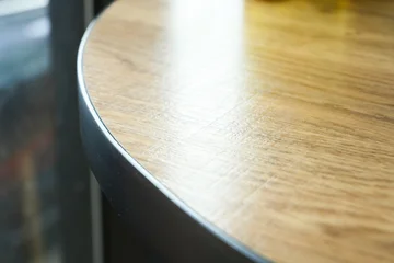 close up detail of a round wooden tabletop with black metal edge © sutichak
