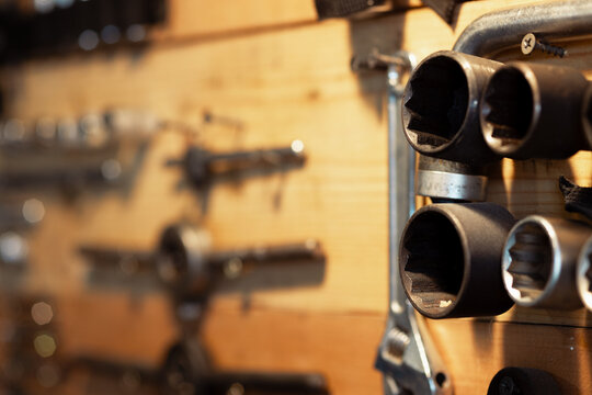 Wooden garage stand with tools for household appliance and transport belts. Traces of wear and dirt on the tools. Socket heads. Selective focus.