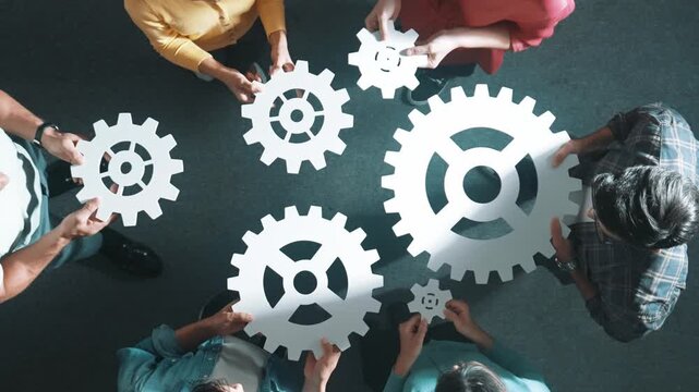 Top down aerial view of business team working together to gather cog together. Aerial view of professional diverse group holding cog and complete white gear. Represented unity, teamwork. Symposium.