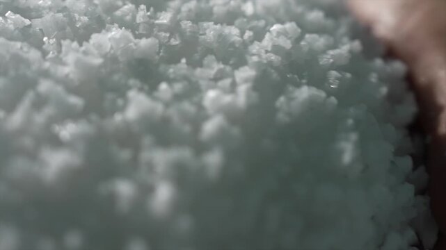 Extreme macro close-up of pure white sea salt crystals held in a hand