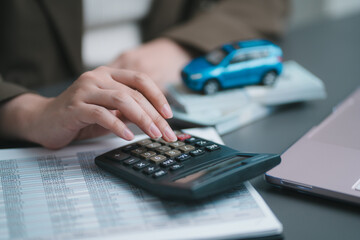 Accountant hand using calculator to check finance document report. Business woman calculating car loan cost, automotive insurance premium and auto tax budget at office desk © winnievinzence