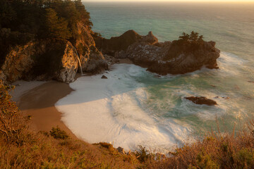 McWay Falls cascades onto the beach in Julia Pfeiffer Burns State Park, Big Sur, California, USA. The ocean waves crash against the rocky shore. © Zenstratus