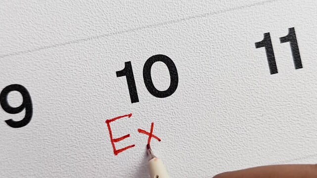 Macro Shot of Writing "Exam" with Red Pen Under Date 10 on Calendar, School Test Day Concept
