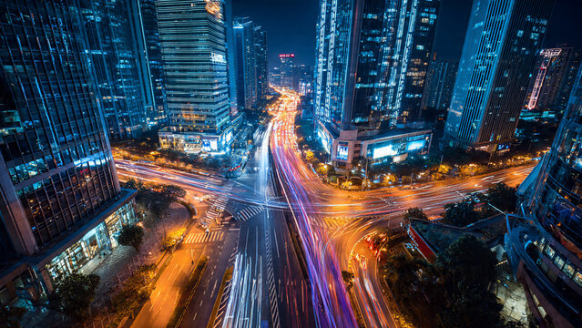 Aerial view of vibrant city intersection at night with light trails from traffic, perfect for urban planning, transportation advertising and corporate business promotion