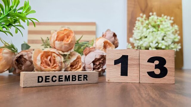 Hand placing wooden calendar blocks showing december 13 on a wooden table