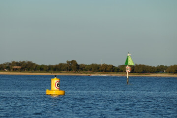Yellow Navigation Buoy and Speed Limit Sign in Coastal Waterway