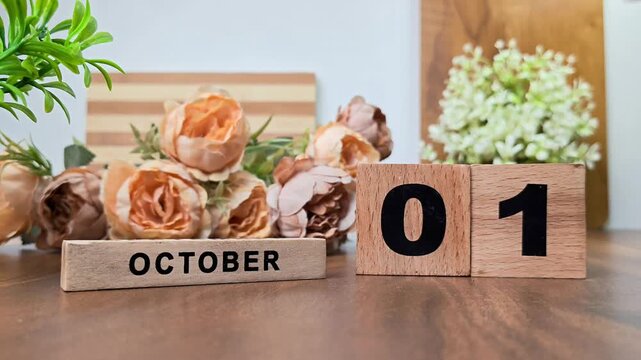 Hand placing wooden calendar blocks showing october 1 on a wooden table