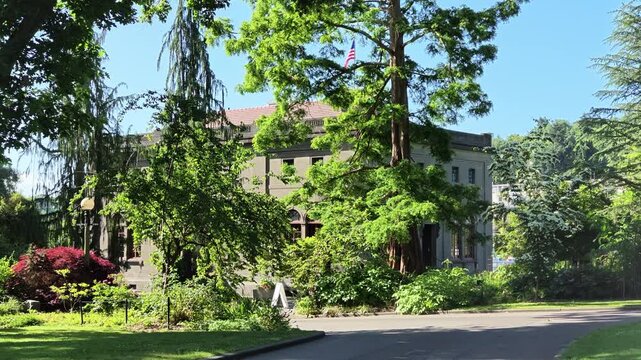 Historic stone mansion with American flag surrounded by lush green trees