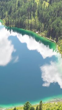 Vertical Aerial video view of Altai mountain lake Uchkol with reflection of blue sky and clouds.
