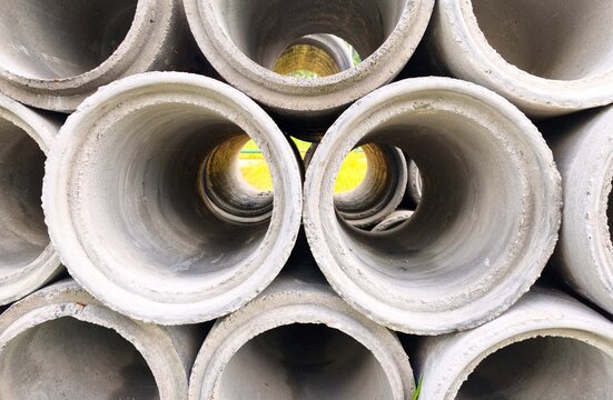 Large concrete drainage pipes stacked with a deep perspective view through the center toward the light.