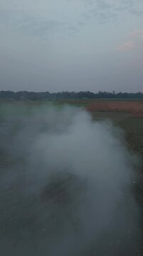 Rural field smoke rising from ground at dusk atmospheric haze over farmland landscape serene