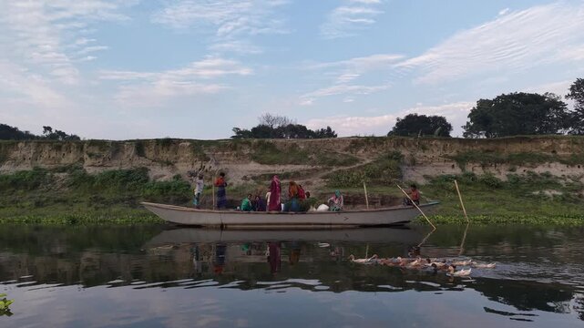 Rural river journey with people on a boat and ducks swimming alongside serene natural landscape
