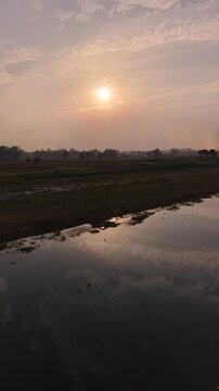 Serene sunrise over rural landscape with reflecting river gentle mist rising from fields golden