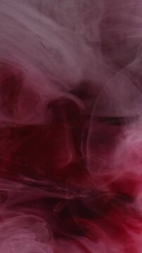 Vertical video. Blend ink. Fume water. Defocused red crimson pink color smoke paint chemical wet fog hovering on abstract ethereal art background.