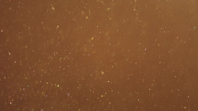 Defocused shine particles. Light glitter dots. Golden yellow circle stream blend glowing powder. Color bokeh luminosity abstract background.
