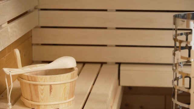 Modern sauna interior with a wooden bucket, ladle, and an electric heater for wellness