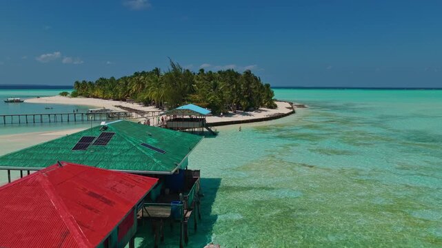 Aerial drone takeoff and vertical ascent over the wooden dock of Onuk Island, Balabac, Palawan, Philippines. Launching flight climbs high above overwater stilt houses and turquoise reef.