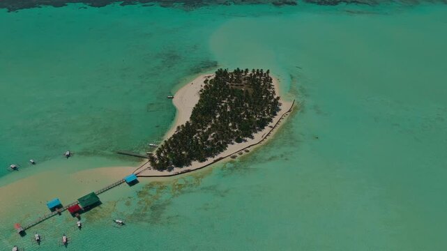 High altitude 45 degree aerial orbit of Onuk Island tracking left to right, Balabac, Philippines. Panoramic drone shot reveals tropical sandbar, overwater bungalows, and deep blue ocean horizon.