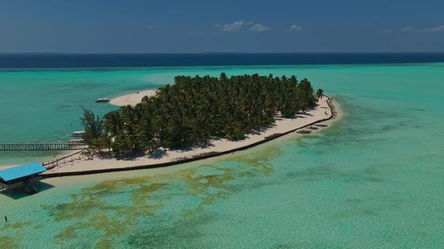 Aerial tracking orbit of Onuk Island moving left to right, Balabac, Palawan, Philippines. Panoramic drone shot reveals tropical paradise, clear turquoise sea, coral reefs, and stilt houses.