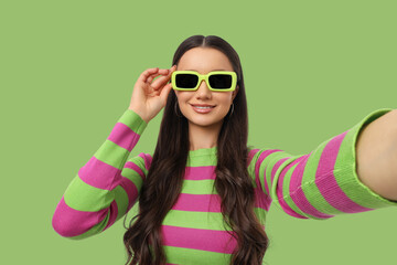 Fototapeta premium A woman smiles while taking a selfie with bright sunglasses