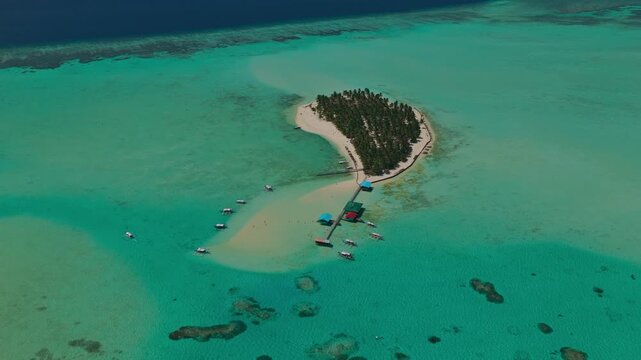 High altitude aerial vertical descent over Onuk Island in Balabac, Palawan, Philippines. Drone drops down revealing a spectacular birds-eye view of the tropical coral reef, sandbar, and stilt houses.