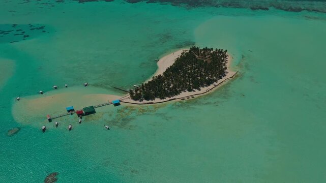High altitude aerial orbit of Onuk Island tracking right to left, Balabac, Palawan, Philippines. Panoramic drone view showcases isolated tropical paradise, massive coral reef system, and overwater sti