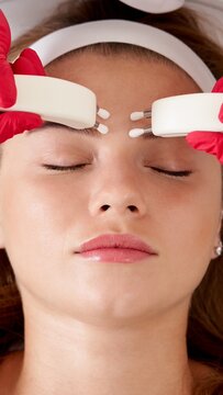 Beautiful Woman in Spa Clinic Receiving Stimulating Electric Facial Treatment From Therapist. Closeup Of Young Female Face During Microcurrent Therapy