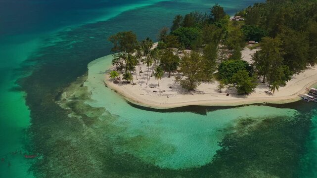 Fast aerial drone orbit shot moving clockwise around Candaraman Island in Balabac, Palawan, Philippines, showcasing vibrant turquoise water and pristine white sand.