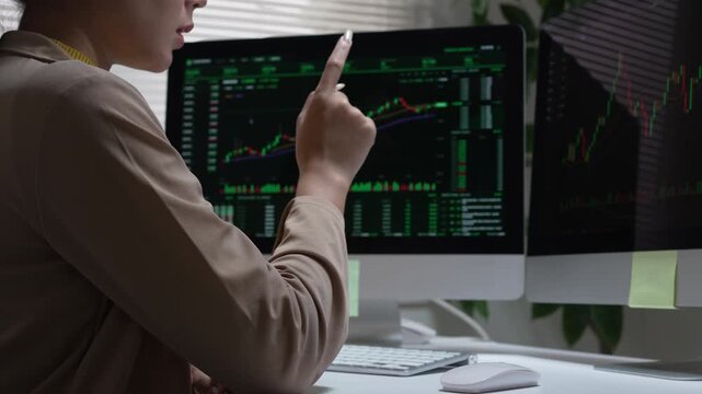 Focused trader and analyst studying stock market chart on computer monitor, checking business finance data in dark office