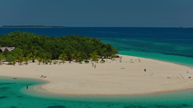Aerial telephoto 2.5x orbit of Patawan Island moving left to right, Balabac, Philippines. Clockwise compressed drone shot showcases tropical island beach and shallow coral reef.