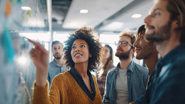 Diverse team collaborating at a whiteboard, pointing and discussing ideas, perfect for business meetings, brainstorming sessions and startup presentations