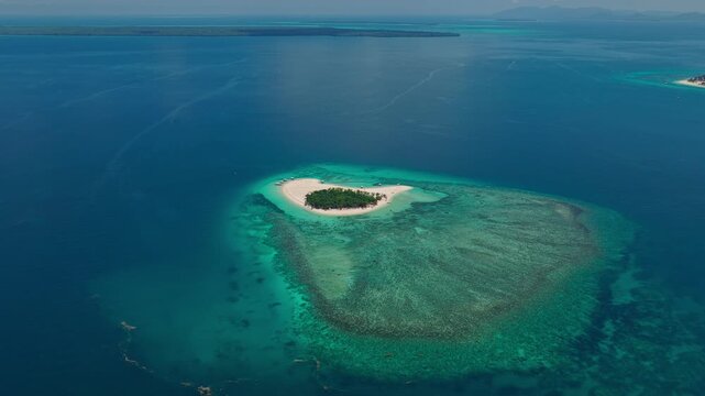 Long distance high altitude aerial approach toward Patawan Island, Balabac, Palawan, Philippines. Wide angle tracking push-in shot reveals remote tropical island ecosystem.