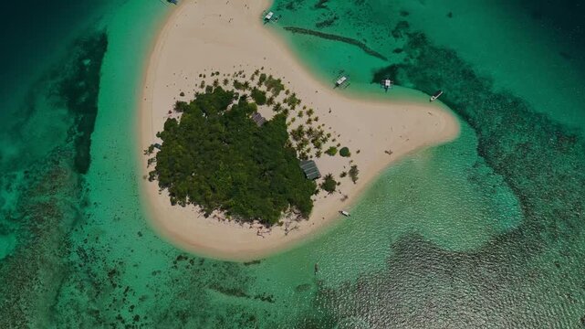 Top down aerial counter clockwise rotation over Patawan Island, Balabac, Palawan, Philippines. Nadir drone twirl shot showcases tropical island canopy, white sand beach, and clear reef patterns.