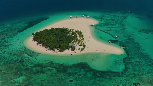 High altitude aerial backward reveal flight of Patawan Island, Balabac, Palawan, Philippines. Reverse tracking drone pull away showcases remote tropical island, white sand beach, and turquoise coral