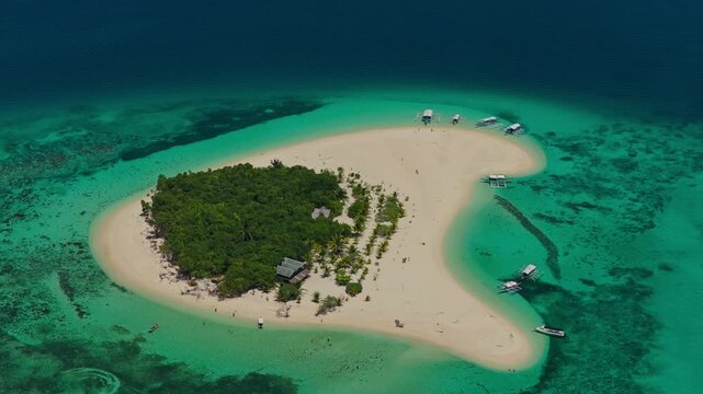High altitude aerial tracking orbit of Patawan Island moving right to left, Balabac, Philippines. Wide angle counter clockwise drone shot reveals remote tropical island and turquoise reef.