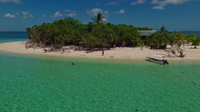 Aerial drone flight descending to land at Patawan Island, Balabac, Palawan, Philippines. Inbound landing approach over clear turquoise water towards tropical sandy beach.