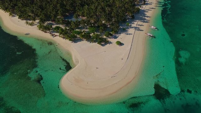 Aerial drone flight flying forward toward Tangkahan Island, Balabac, Palawan, Philippines. Straight tracking shot over transparent turquoise ocean reveals tropical hook-shaped sandbar.