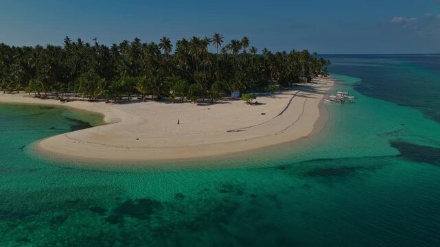 Aerial tracking orbit of Tangkahan Island moving left to right, Balabac, Palawan, Philippines. Panoramic drone shot reveals tropical hook-shaped sandbar, palm trees, and turquoise reef.