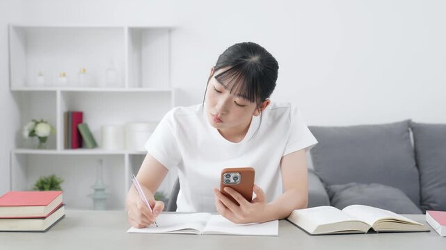 スマホを見ながら勉強する10代女性