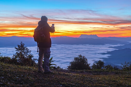 Male Hiker with backpack using smartphone taking photos mountains landscape. Sharing travel lifestyle and adventure vacations. Use outdoor modern technology