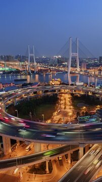 Cityscape day to night transition vertical panning time lapse of Nanpu bridge illuminated at night with, with evening time rush hour commuters