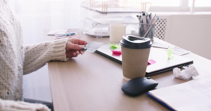 Mobile payment. Online shopping. Unrecognizable business woman typing information on smartphone using credit card for cashless transfer at workplace.